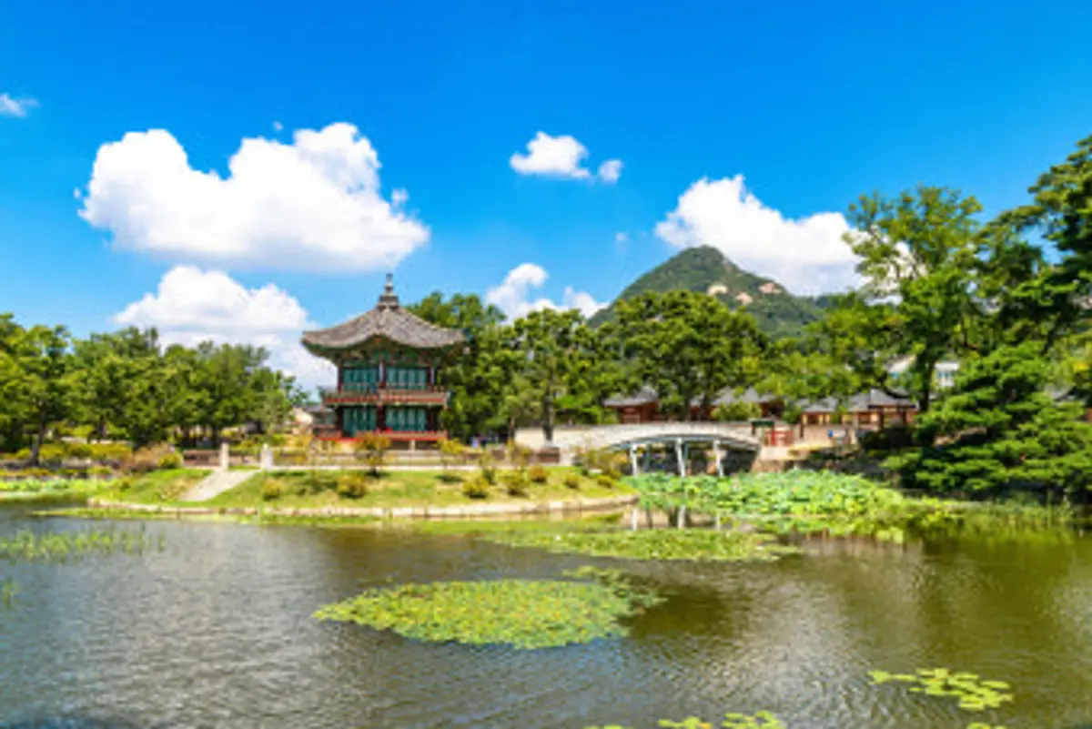 Hyangwonjeong Pavilion on its lotus pond at Gyeongbokgung Palace, framed by summer trees and Bugaksan