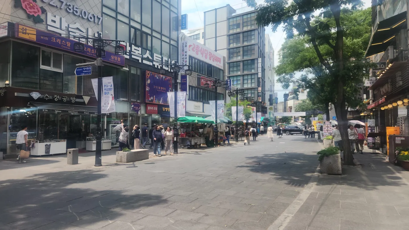 真昼の陽光の下、韓服スタジオ、工芸品店、夏の散策者で賑わう鍾路の歩行者専用通り、仁寺洞通り