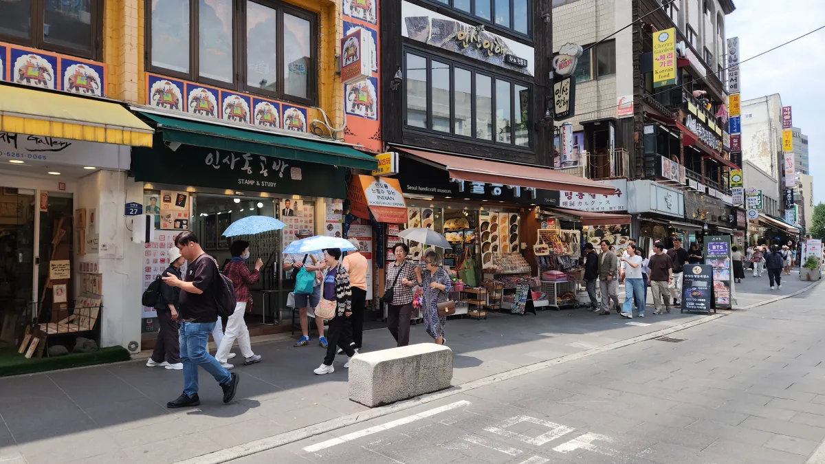 ソウル鍾路、仁寺洞のメインストリート沿いの工芸品店やギャラリーの前を日傘を差して歩く来訪者たち