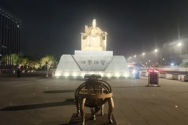 밤의 광화문 광장에 자리한 세종대왕 동상과 혼천의가 조명을 받아 빛나는 모습
