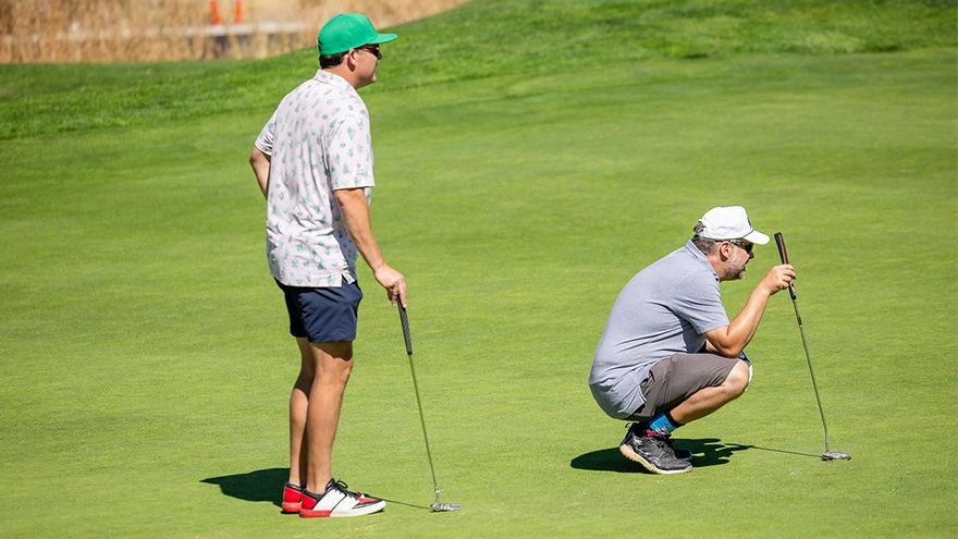 Two participants watching path of golf ball.