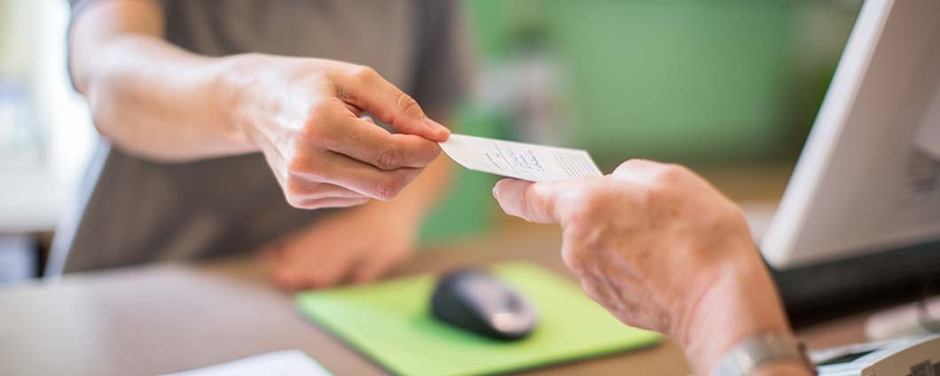 Patient handing insurance card to staff