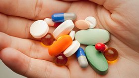 A hand holding a variety of medical pills