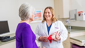 A female doctor is talking to an older woman in a purple shirt