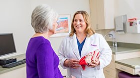 A female doctor is talking to an older woman in a purple shirt