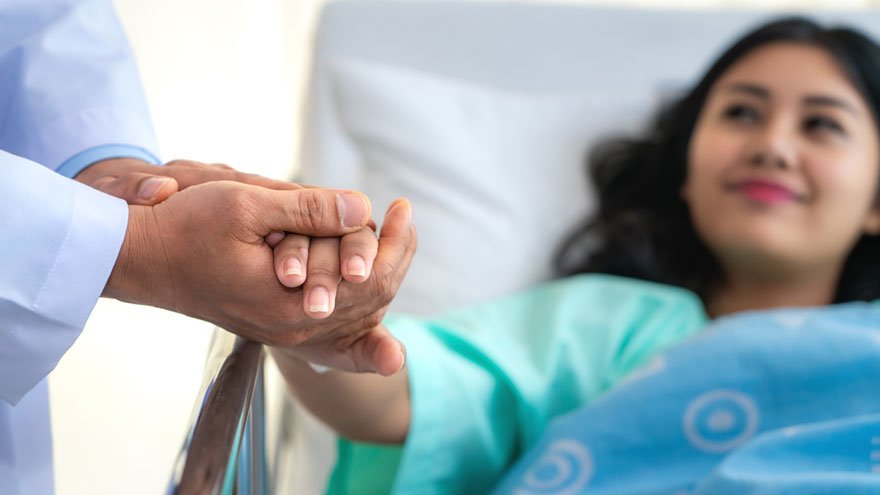 Patient in hospital bed being comforted by her doctor
