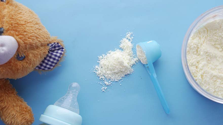 teddy bear next to baby bottle and baby formula powder