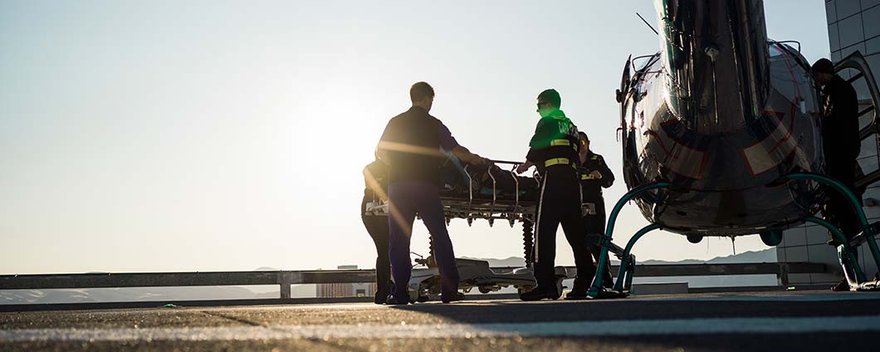 Medical team transporting patient on rooftop of hospital next to helicopter