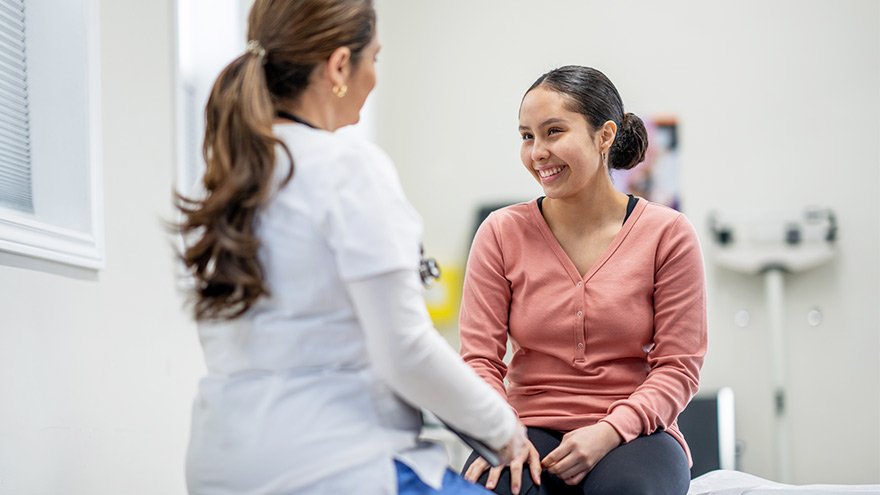 A doctor speaks with a teen patient