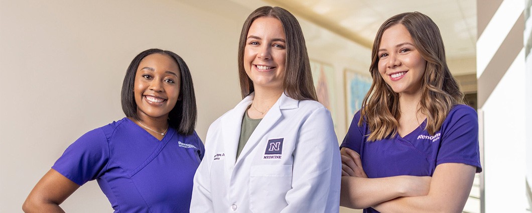 three women in scrubs and lab coats are posing for a picture .