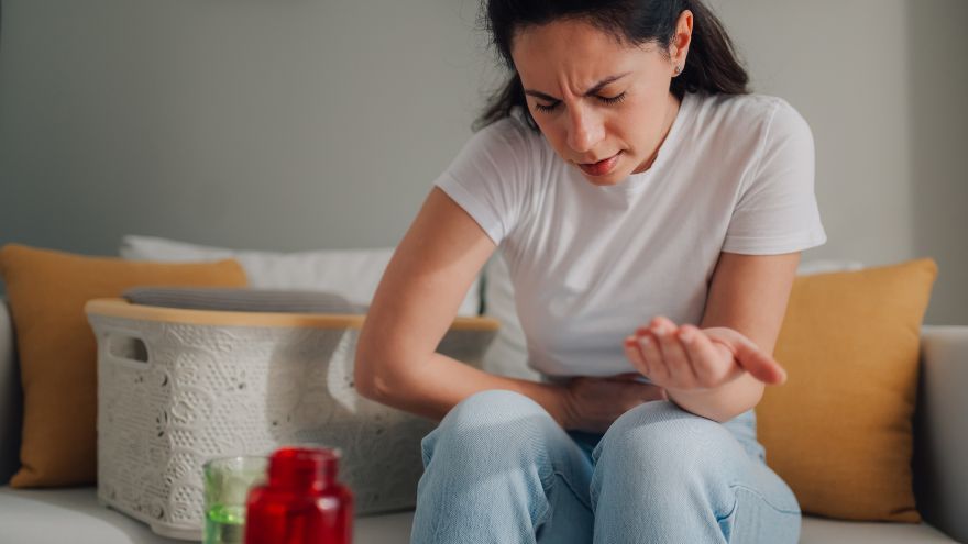 Woman sits holding stomach in pain from UTI