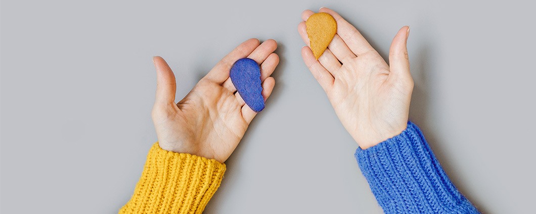 Hands holding two pieces of a broken heart