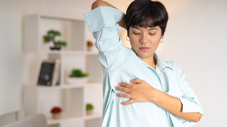 Frontal photo of a Latin woman doing self breast exam at home