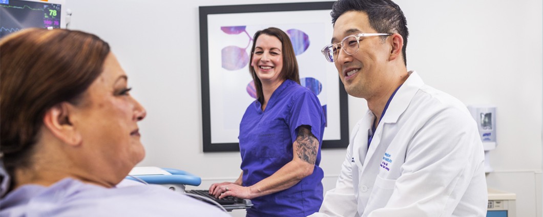 Dr. Eric Kim, Renown Health Urologist, consults with patient as nurse looks on