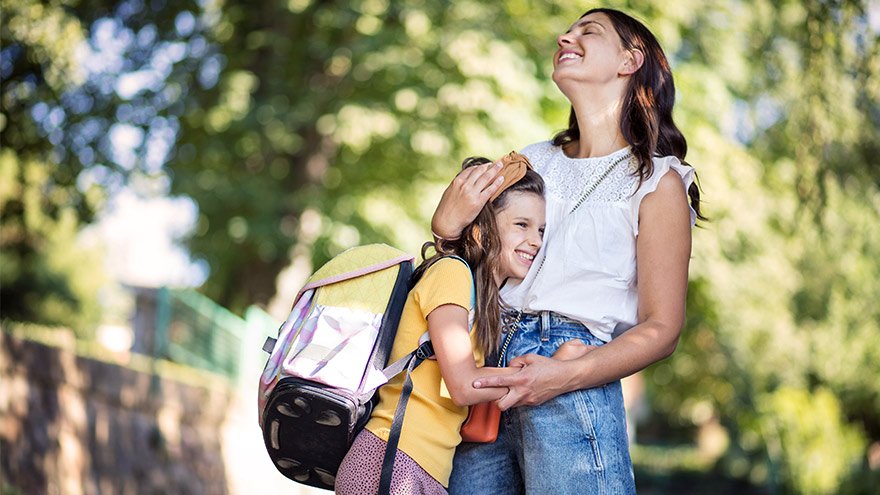 Mother and daughter embrace as they walk to school together