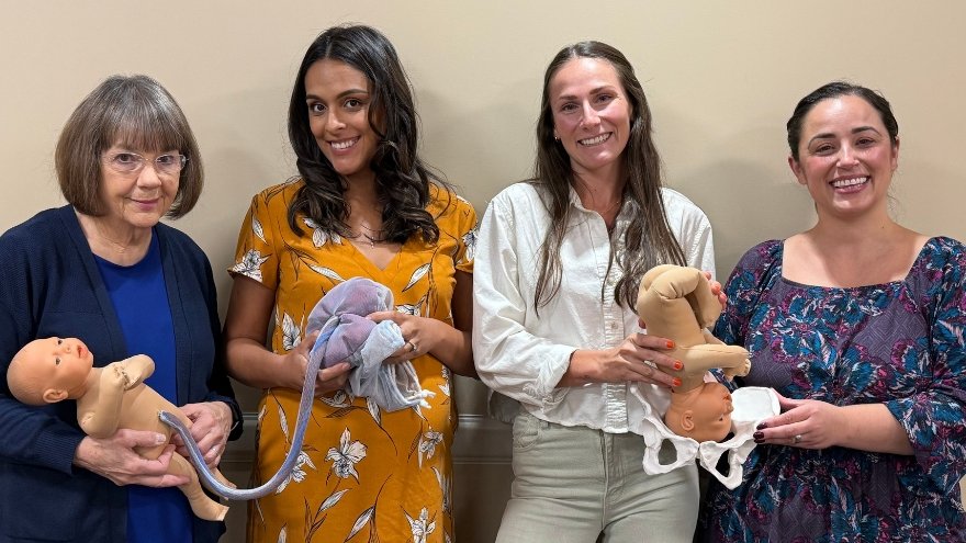 Four members of Renown's Maternal Child Education team pose for a group photo with tools and equipment from their classes.