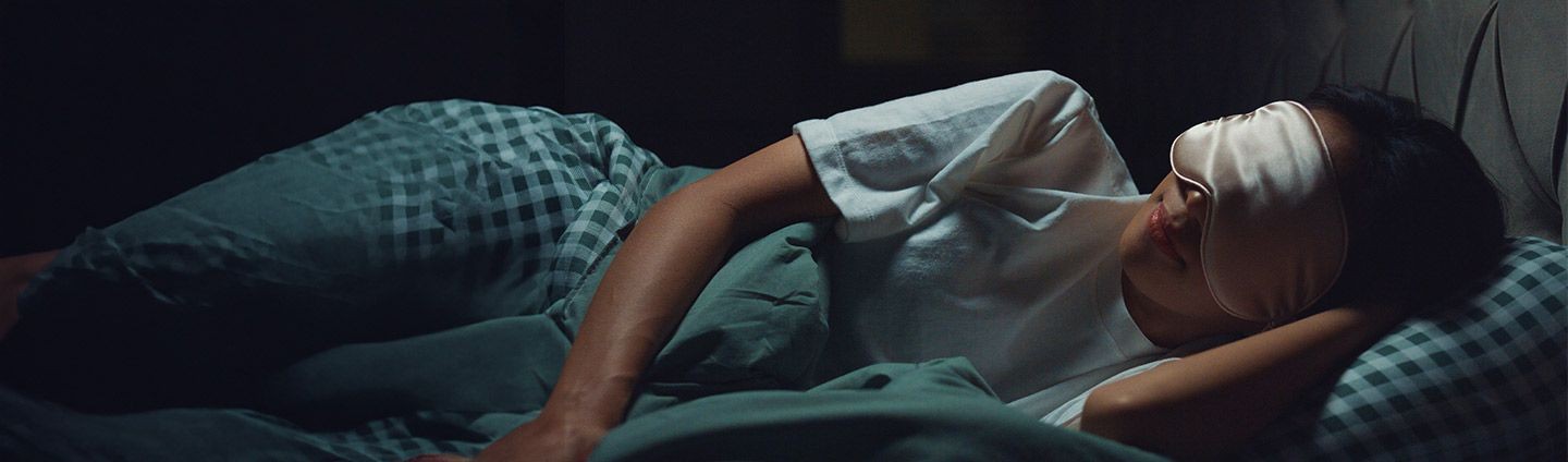 Woman sleeping with eye mask in a calm, dark room