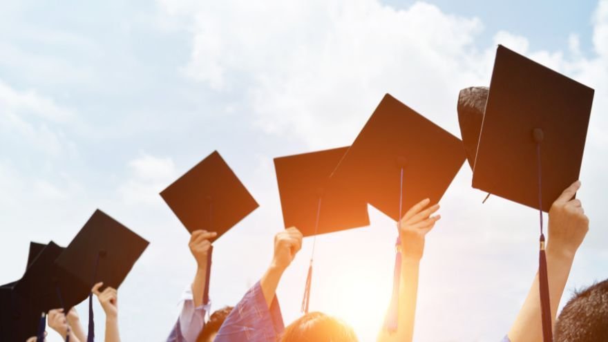Graduates holding caps above their heads