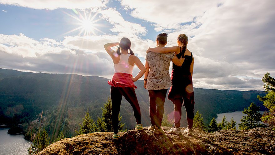 Three young women overlooking valley while on a hike
