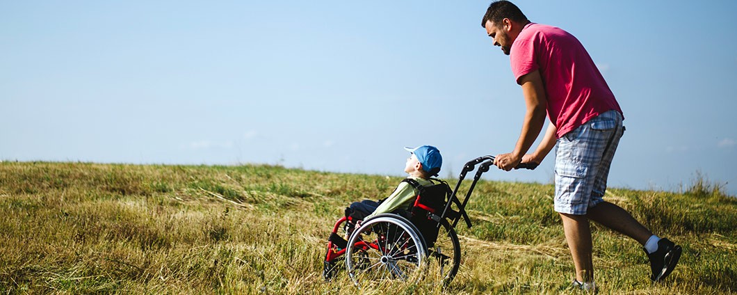 Dad pushing son in wheelchair