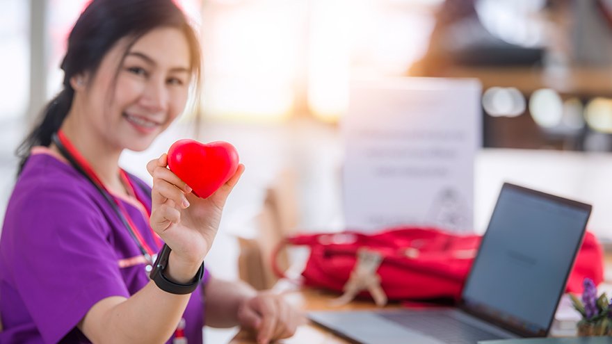 Nurse in purple uniform sitting and holding red heart