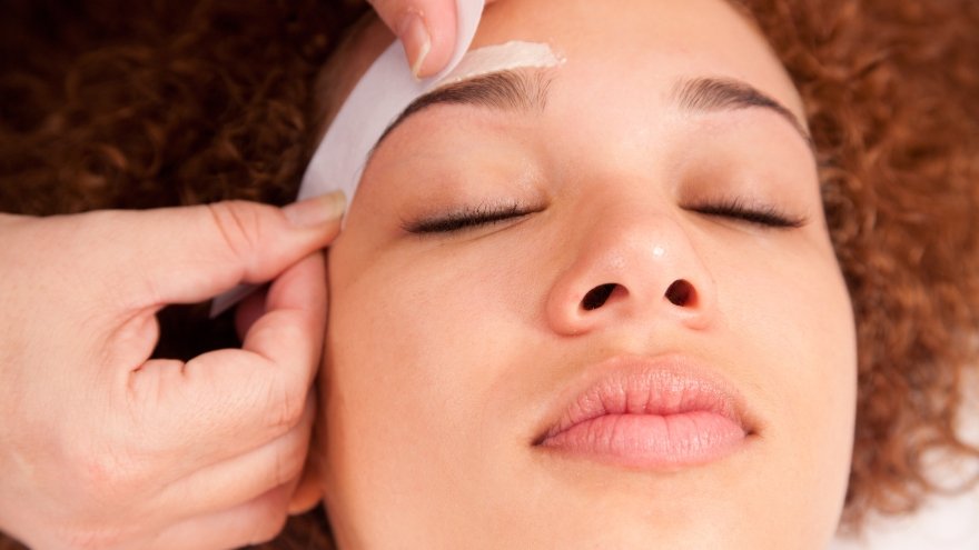 Woman having her eye brows waxed.