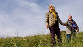 A couple in a grass field holding hands and smiling