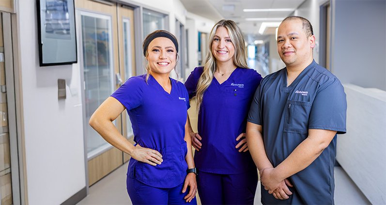 Three renown providers posing closely in hallway.
