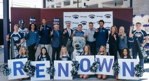 Renown Health and University of Nevada leaders, student-athletes, cheerleaders and the Wolf Pack mascot pose in front of a Renown and Nevada step-and-repeat banner, holding letters spelling RENOWN.