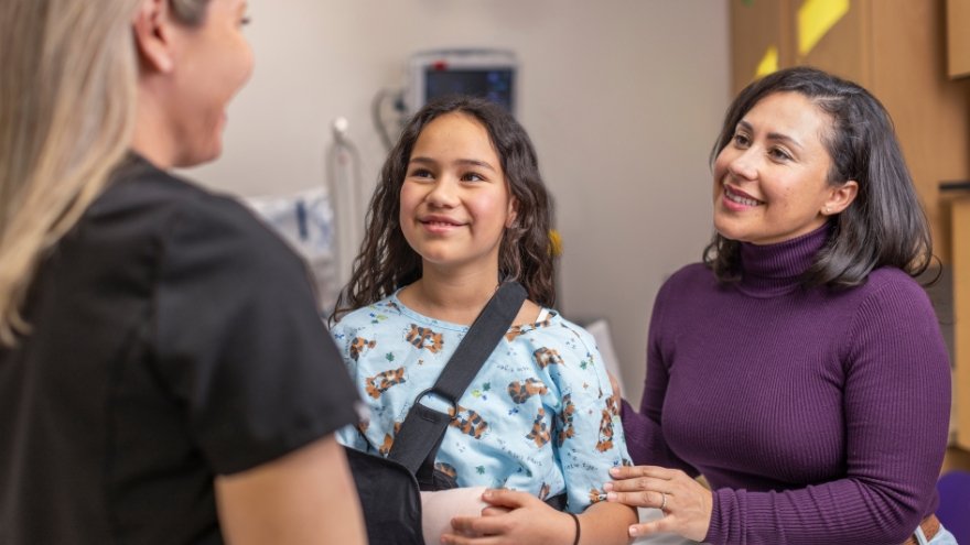 a woman is talking to a girl with a broken arm in a hospital room.