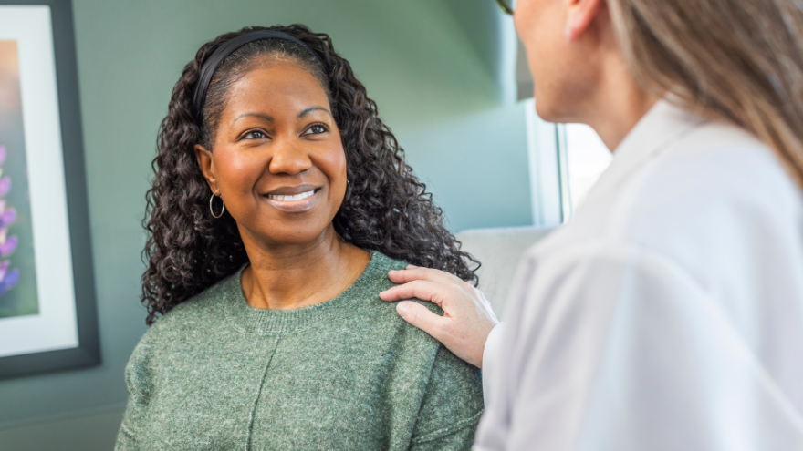 A photo of a breast care patient smiling at her doctor
