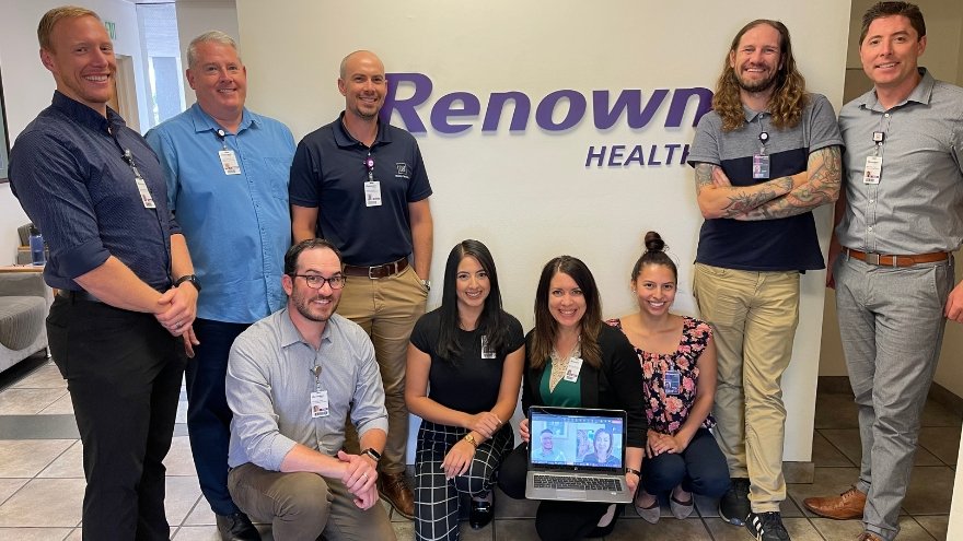 Team members from the Transformation Management Office pose for a group photo (both in-person and online) outside their office at 1000 Ryland Street.