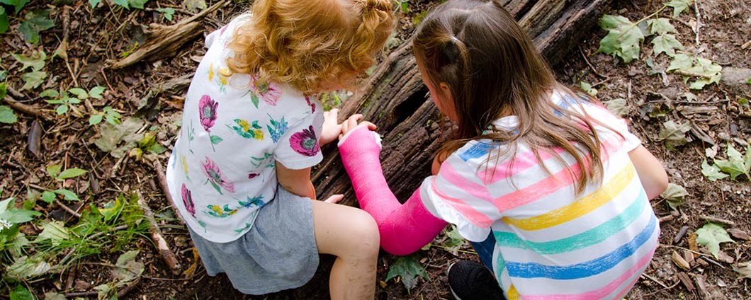 Girl in cast playing with friend outdoors