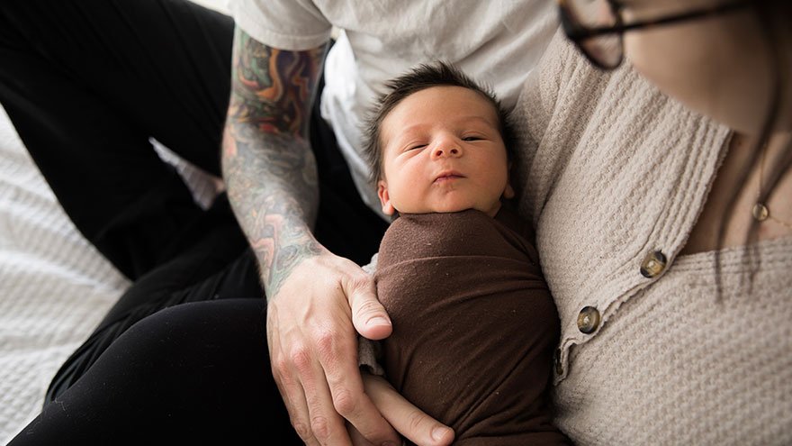 Swaddled newborn being held by parents