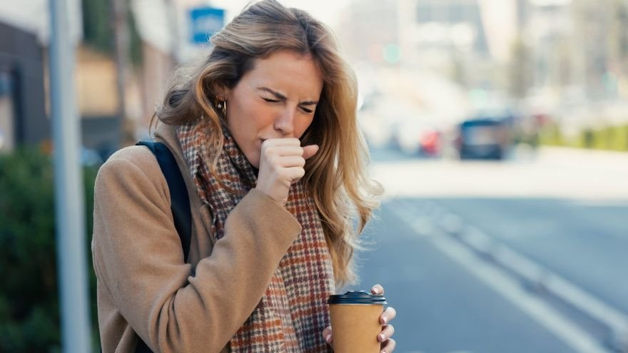 Woman coughing into hand