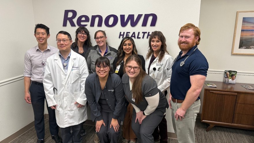 The Infectious Disease team at Renown Health pose in front of the Renown Health logo on a white wall.