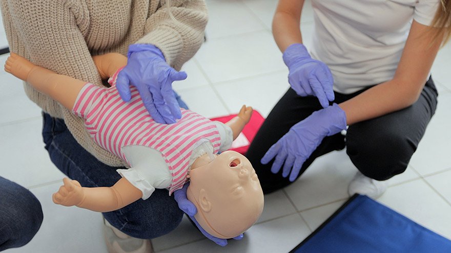 Closeup of first aid instructor using infant dummy demonstrating how to rescue a suffocating baby