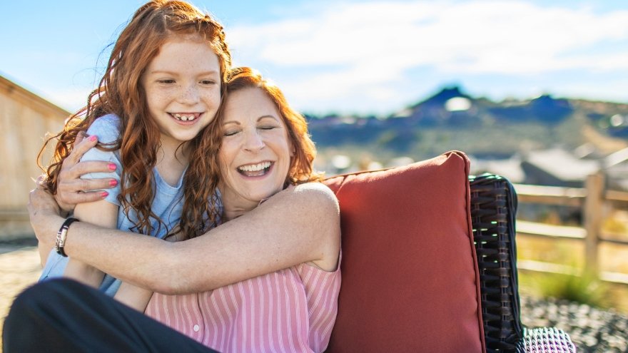 Mom hugging daughter outside in back yard