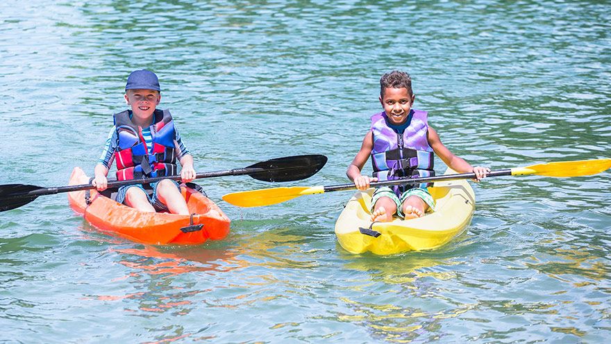Two diverse little boys kayaking on a beautiful lake