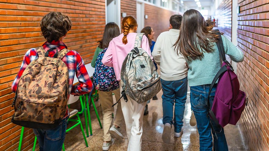 Group of students rushing through a school hallway, carrying backpacks and chatting excitedly as they transition between classes