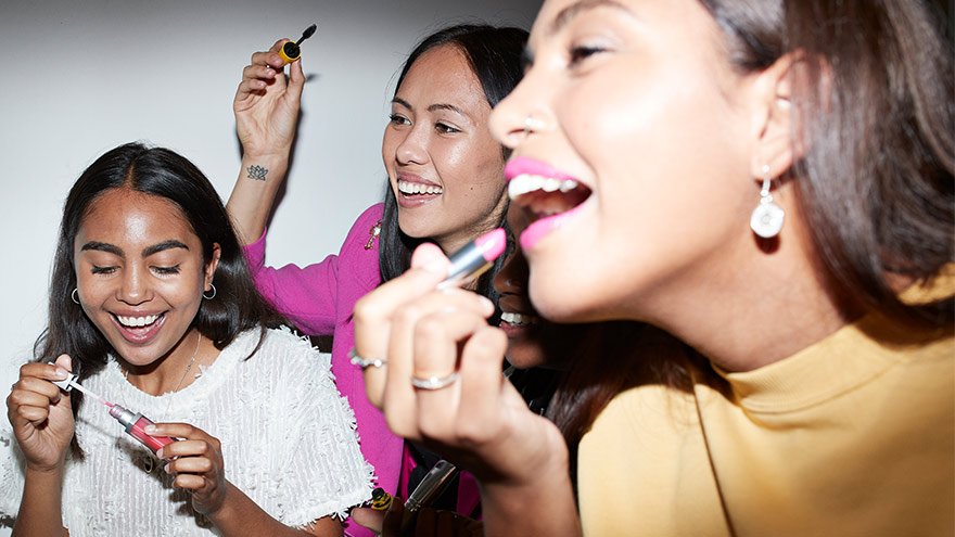 Women having fun using makeup brushes