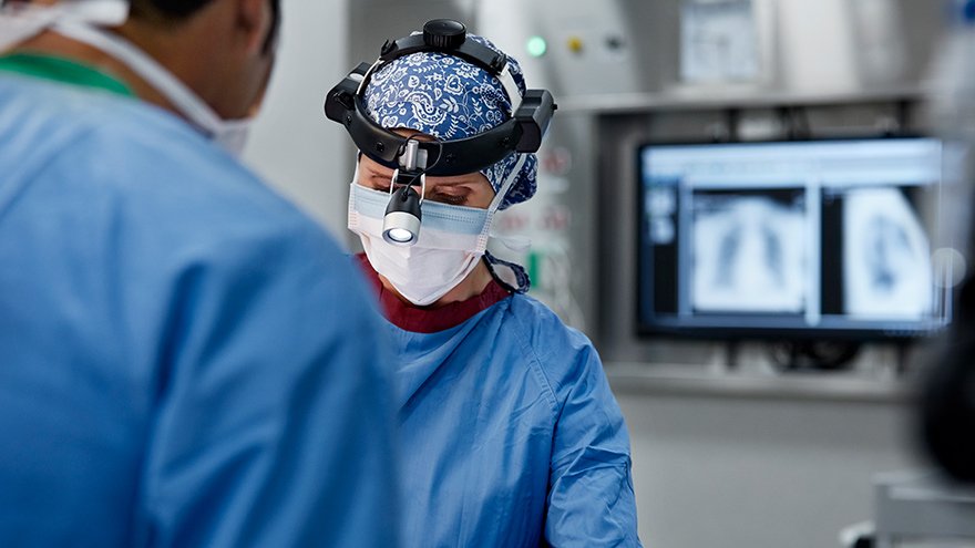 Female neuro surgeon wearing headlamp in operating room