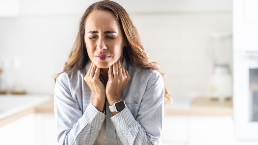Woman holding her throat seemingly painful