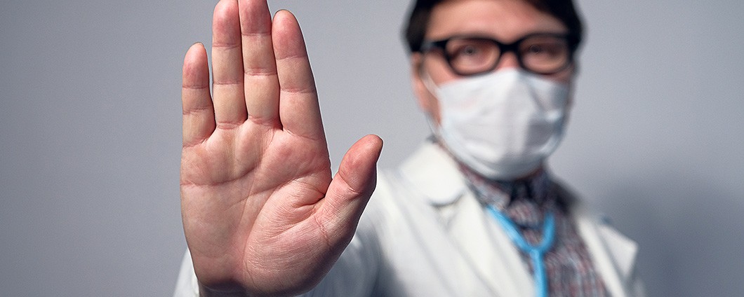 Male doctor in mask putting up hand