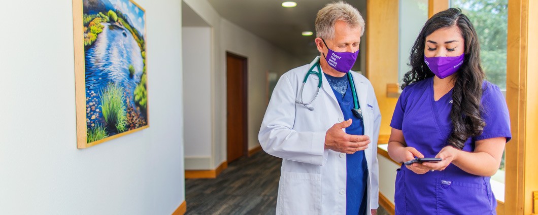 Renown doctor and nurse looking at phone in hallway