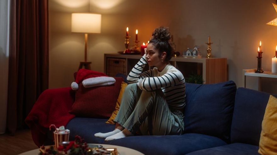 A woman sits on a couch to reflect surrounded by holiday decor