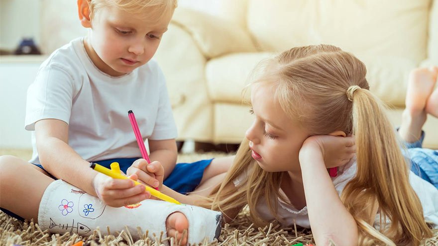 Little boy and girl drawing on his leg cast