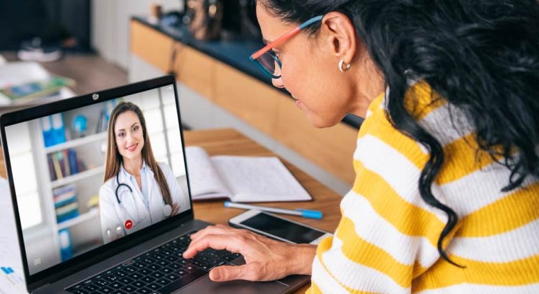 Mother talking with doctor on laptop during virtual visit.