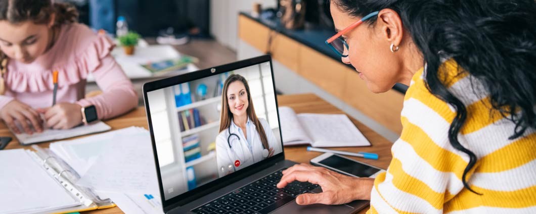 Mother talking with doctor on laptop during virtual visit.