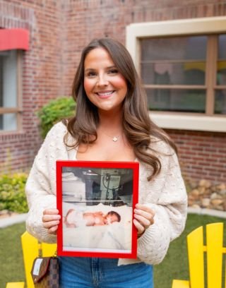 NICU grad posing with photo from time spent in NICU